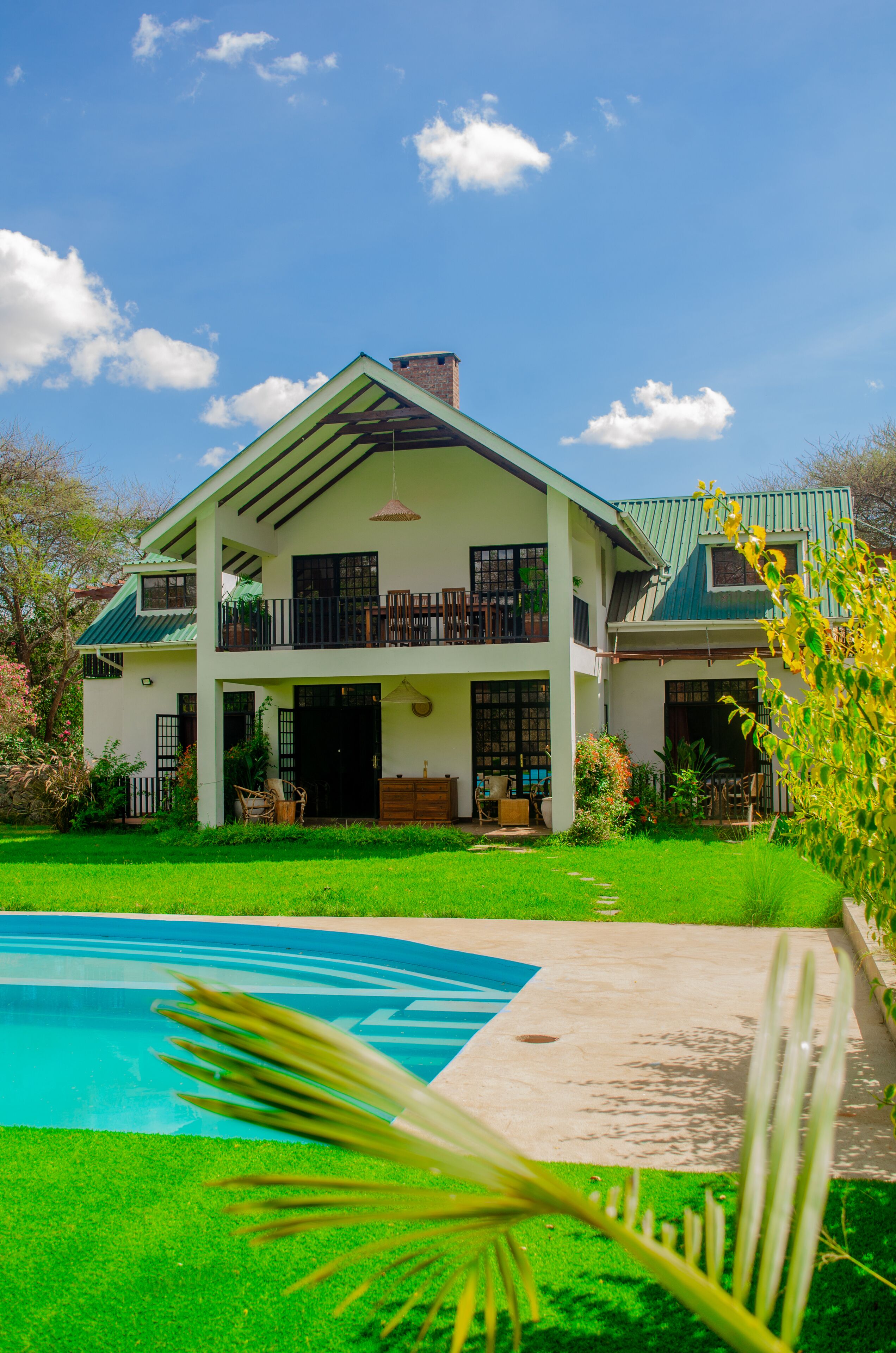 Una casa de dos pisos con piscina, balcón y un jardín bien cuidado.
