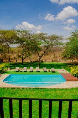 A swimming pool with lounge chairs, surrounded by grass and trees. - Amani Farmhouse (Arusha)