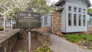 Une plaque commémorative « Gold Star » est placée devant un bâtiment dont la façade est en pierre et recouverte de bardage.