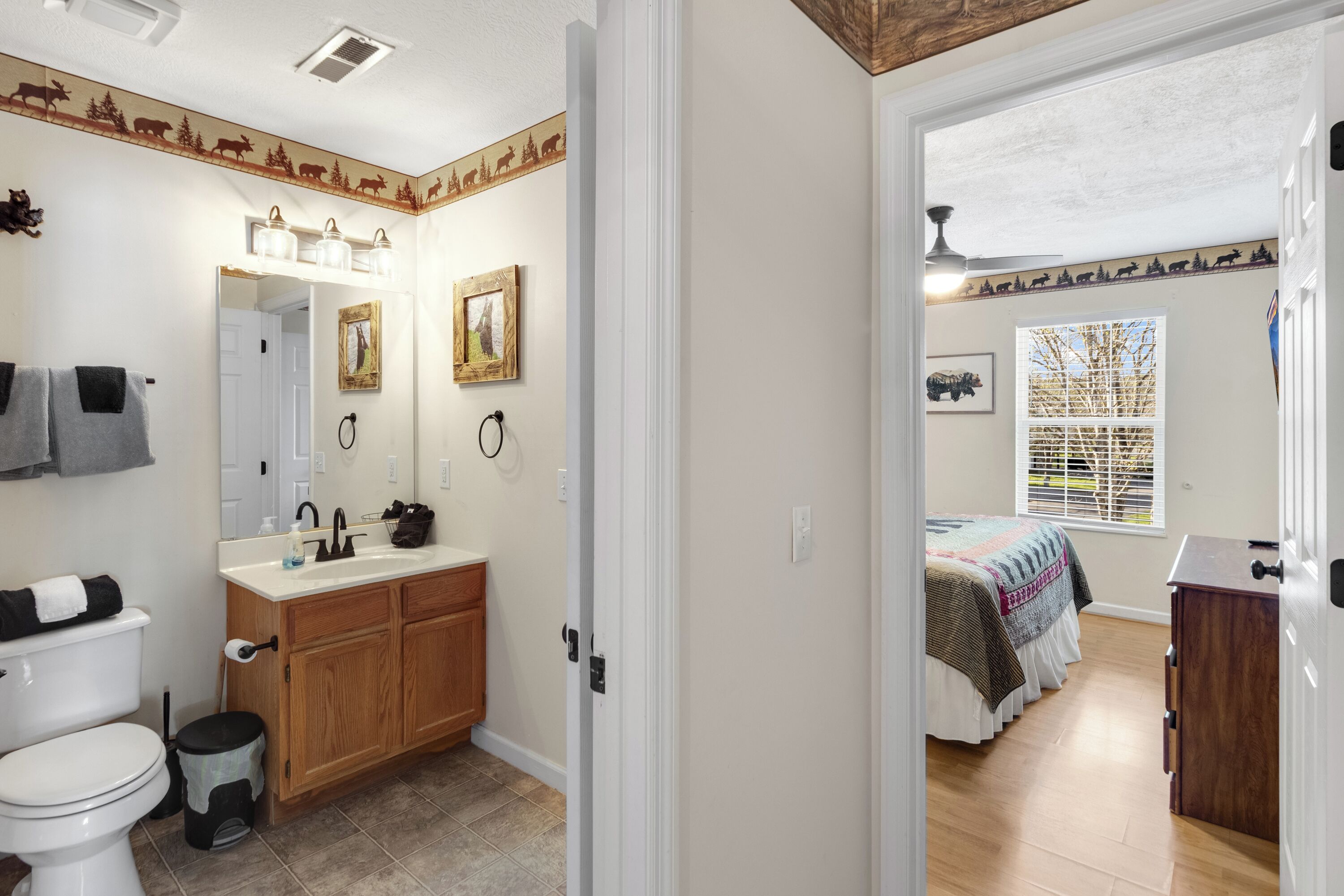 Une salle de bain avec des toilettes, un lavabo et un meuble-lavabo, et une chambre avec un lit et une fenêtre.