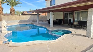 Ein Pool mit geschwungener Form, eine Terrassenanlage mit Gartenmöbeln und eine Mauer aus Stein.