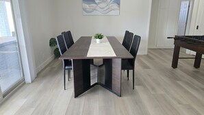 Ein Esszimmer mit dunklem Holztisch, schwarzen Stühlen, einer weißen Tischläufer und einer Zimmerpflanze.