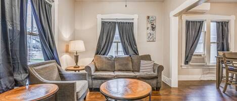 A cozy living room with a sofa, two armchairs, a coffee table, and a dining area with a table and chairs.