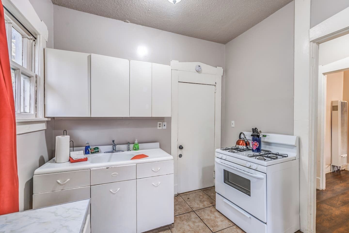 A compact kitchen with white cabinets, a sink, a stove, and a small countertop.