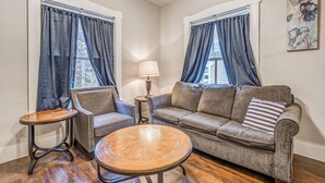 Een woonkamer met een bank, twee fauteuils, een salontafel en een lamp.