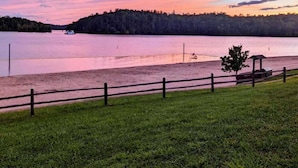 A lakeside view with a wooden fence, a small gazebo, and a boat on the water.