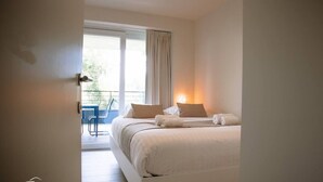 A hotel room with a bed, pillows, a window, and a view of the outside. - SAND–Modern apartment with garage near the beach (Ostend)