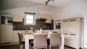 Eine moderne Küche mit Esstisch, gedeckt für vier Personen, ausgestattet mit Backofen und Dunstabzugshaube.
