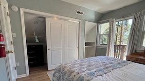 Una camera da letto con un letto, un armadio, una finestra con tende e una porta che dà su un'altra stanza.