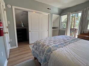 A bedroom with a bed, a closet, a window with curtains, and a door leading to another room. - Charming North Lake Tahoe cabin near beaches and trails. (Tahoe Vista)
