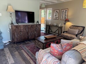 A living room with a TV, wooden cabinet, patterned sofa, and a rug. - Charming North Lake Tahoe cabin near beaches and trails. (Tahoe Vista)
