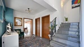 Un interior moderno con una escalera, un escritorio con lámpara, un espejo y un tapete colorido.