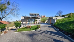 Una casa moderna de dos pisos con un porche cubierto, camino de entrada de grava y jardín en pendiente.