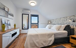 A bedroom with a bed, bedside table, dresser, and a large window. - Beautiful home in Banfi (Banfi)