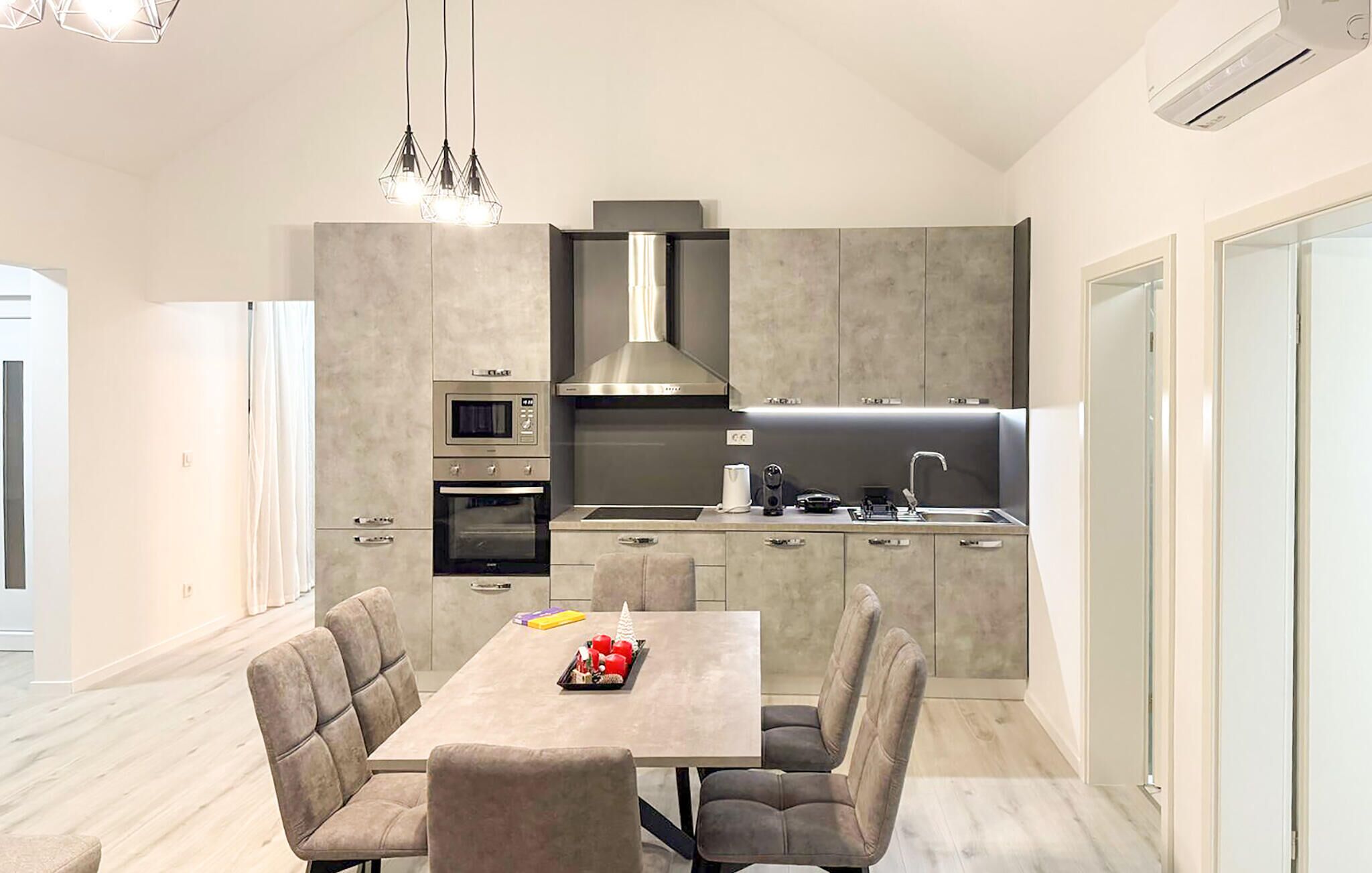 A modern kitchen with a central island, built-in appliances, and a dining area with chairs.