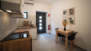 Eine moderne Küche mit Einbauofen, kleinem Kühlschrank und Spüle. Ein Essbereich mit Holztisch und Stühlen ist ebenfalls vorhanden.