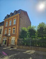 Un edificio en esquina con fachada de ladrillo, varias ventanas y una cerca metálica al frente.