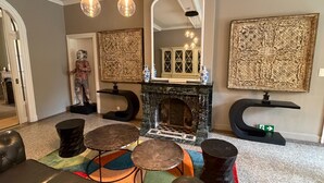 A living room with a fireplace, a statue, and a mirror. - Villa Damseaux (Spa)