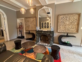 Una sala de estar con chimenea, una estatua y un espejo.