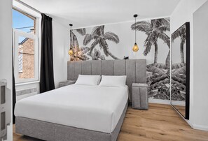A bedroom with a large bed, a grey headboard, bedside tables, and a wall with a tropical leaf pattern. - Villa Damseaux (Spa)