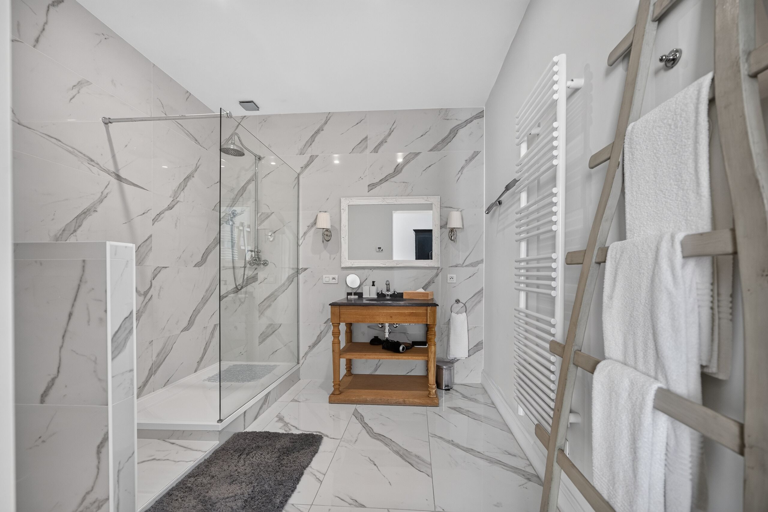 A modern bathroom with a glass-enclosed shower, a wooden vanity, and a towel rack.