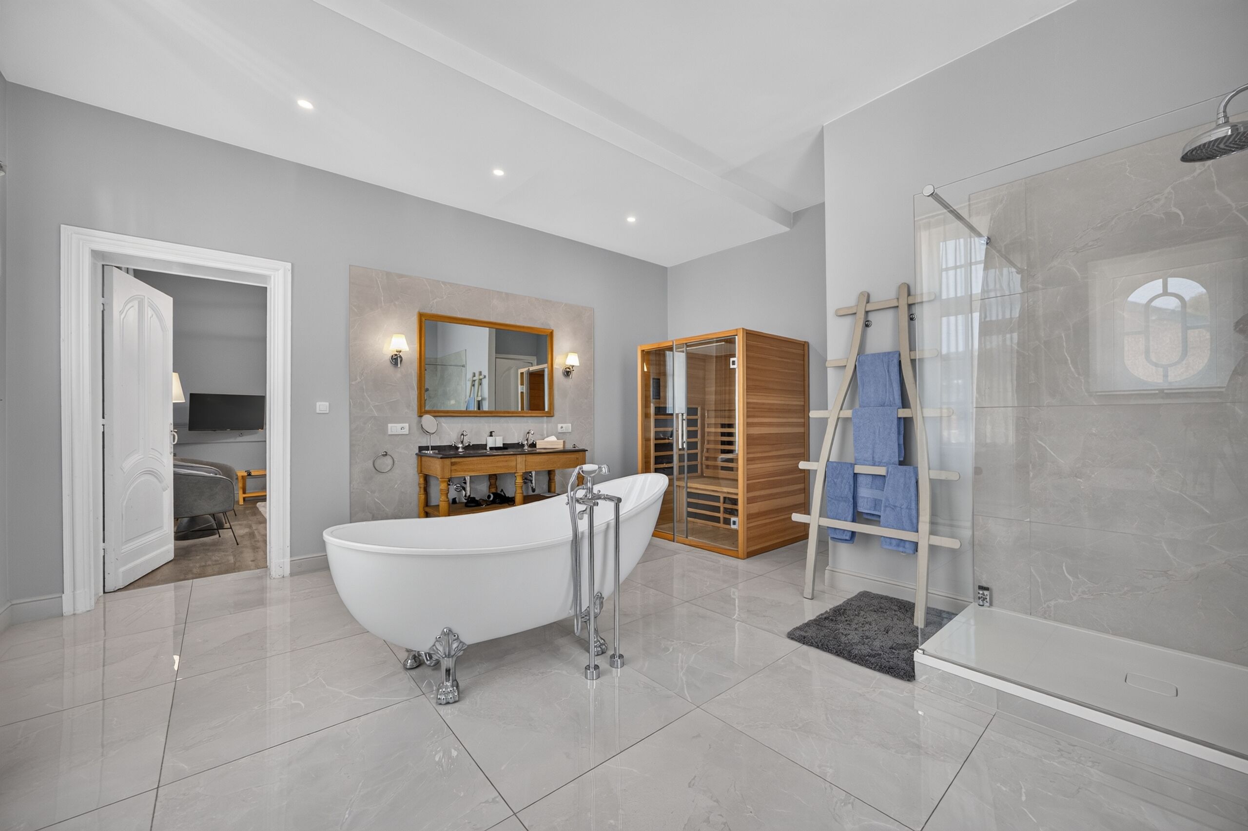 Un baño moderno con una bañera independiente, ducha con mampara de vidrio y tocador de madera.