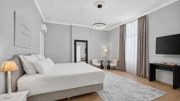 Ein modernes Hotelzimmer mit einem großen Bett, Nachttischen, einem Schreibtisch, einem Flachbildfernseher und einem großen Fenster mit Vorhängen.