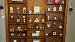 A billiards table with a cue ball in the center, surrounded by a wooden clock display case with various timepieces. - Villa Damseaux (Spa)