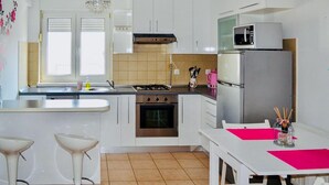 Una cocina moderna con armarios blancos, un refrigerador de acero inoxidable, un microondas, una estufa y un lavaplatos.