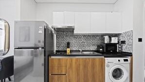 A compact kitchen with a stainless steel refrigerator, a washing machine, and a microwave. - 106 Bloomfields Executive STU Gate Masdr (Madinat Zayed)
