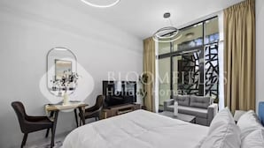 A modern hotel room with a large bed, a desk with a chair, a television, and a sofa. - 106 Bloomfields Executive STU Gate Masdr (Madinat Zayed)