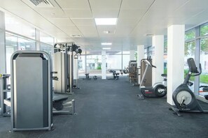 Une salle de sport équipée de divers appareils d’exercice, dotée de grandes fenêtres et présentant un design moderne et épuré.