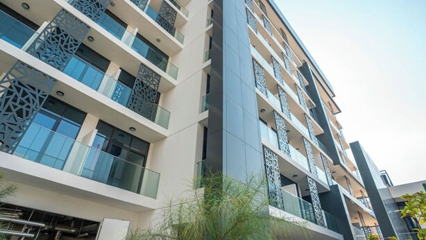 A multi-story hotel with balconies, large windows, and a modern architectural design. - 106 Bloomfields Executive STU Gate Masdr (Madinat Zayed)