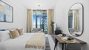 A hotel room with a bed, a dining table with chairs, a large mirror, and a view through a window. - 106 Bloomfields Executive STU Gate Masdr (Madinat Zayed)