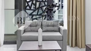A modern living room with a grey sofa, a white vase, and a glass table. - 106 Bloomfields Executive STU Gate Masdr (Madinat Zayed)