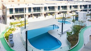 A modern building with a swimming pool, outdoor seating, and a landscaped area. - 106 Bloomfields Executive STU Gate Masdr (Madinat Zayed)
