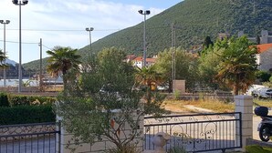 Un espace extérieur clos, agrémenté d’un jardinière en pierre, de palmiers et, en arrière-plan, d’une montagne.