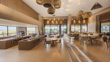 Un hall d’hôtel spacieux comprenant un espace buffet, des coins salon et de grandes fenêtres donnant sur l’extérieur.