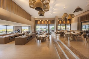 A spacious hotel lobby with a buffet area, seating arrangements, and large windows offering a view of the outdoors. - Medite Kassandra Resort (Nea Propontida)