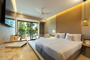 A modern hotel room with a large bed, a ceiling fan, a balcony with outdoor seating, and a view of greenery. - Medite Kassandra Resort (Nea Propontida)