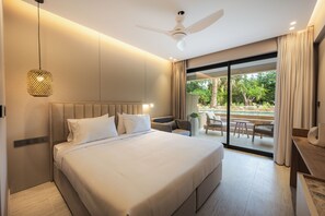 Une chambre d’hôtel moderne dotée d’un grand lit, d’un ventilateur de plafond, d’un coin repas avec des sièges extérieurs, et offrant une vue sur une piscine et un espace verdoyant.