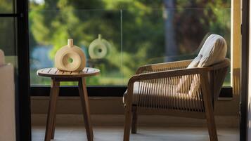 A wicker chair and a small round table with a vase in a room with a large window.