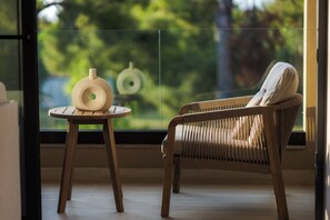 A wicker chair and a small round table with a vase in a room with a large window. - Medite Kassandra Resort (Nea Propontida)