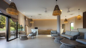Ett modernt loungeområde med sittplatser, en receptionsdisk och stora fönster.