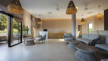 A modern lounge area with seating, a reception desk, and large windows.