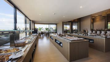 A modern buffet setup with multiple serving stations, a central island, and a view of the outdoors.