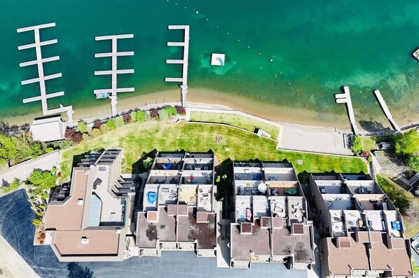 Vue aérienne d’une zone résidentielle côtière comprenant plusieurs immeubles d’appartements, une plage et un port de plaisance.