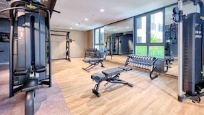 Une salle de sport moderne dotée de divers équipements d’exercice, de grandes fenêtres et d’un aménagement propre et spacieux.