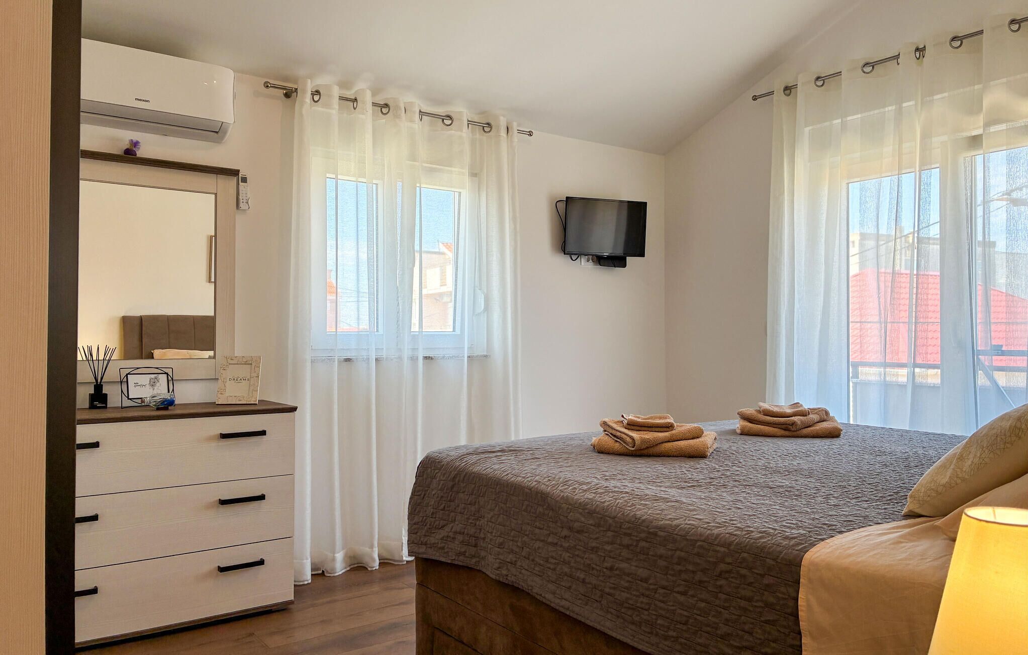 Ein Schlafzimmer mit einem Bett, einem Fernseher, einer Kommode und einem Fenster mit Vorhängen.
