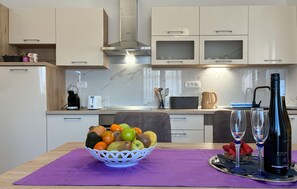 A modern kitchen with a fruit bowl, wine bottle, and glasses on the table. - Beautiful apartment in Vir with WiFi (Vir)